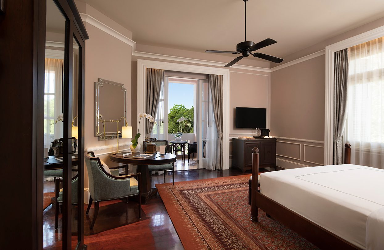 Newlook of Landmark Room at the Raffles Grand d’Angkor with warm hardwood floors, lighter interiors, charming ceiling fan & brass telephone